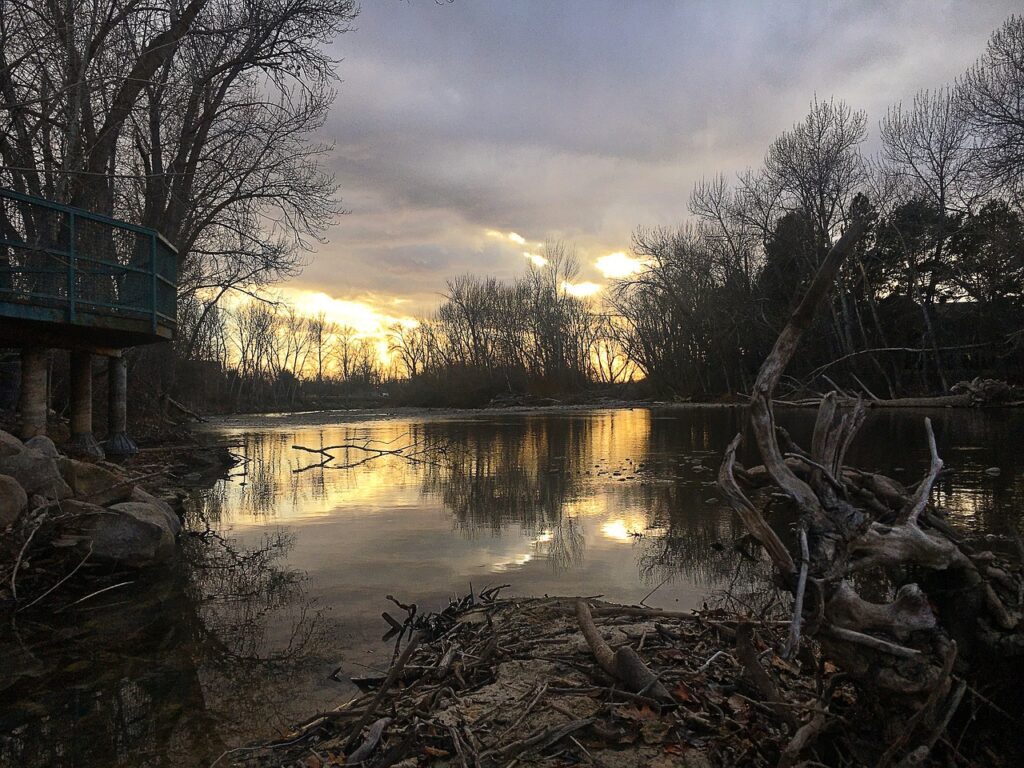 The Boise River at sunset, with a scenic landscape of water, sky, and forested surroundings in winter.