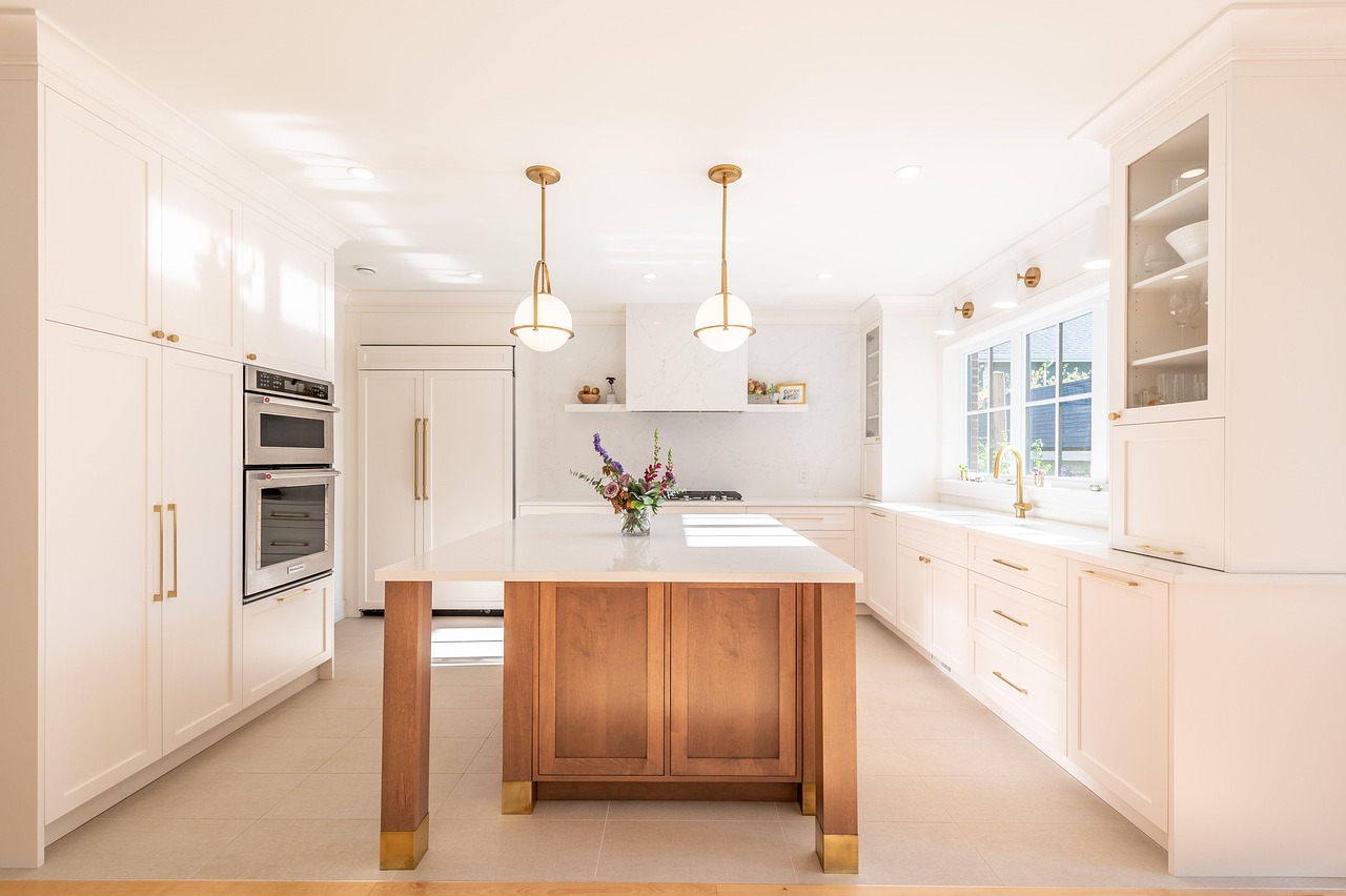 White kitchen with a wood island and brass pendant lights