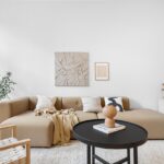 A luxury living room featuring a sofa, wooden floor, carpet, chairs, decorative pillows, a cabinet, lamp, window, and wall art.