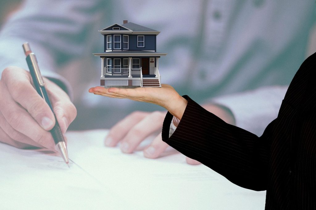A hand giving or signing a real estate contract document, representing a property sale, mortgage, or rental agreement.
