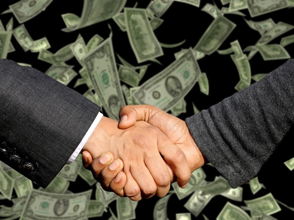 Two people shaking hands over a business agreement, symbolising a commercial deal or contract.