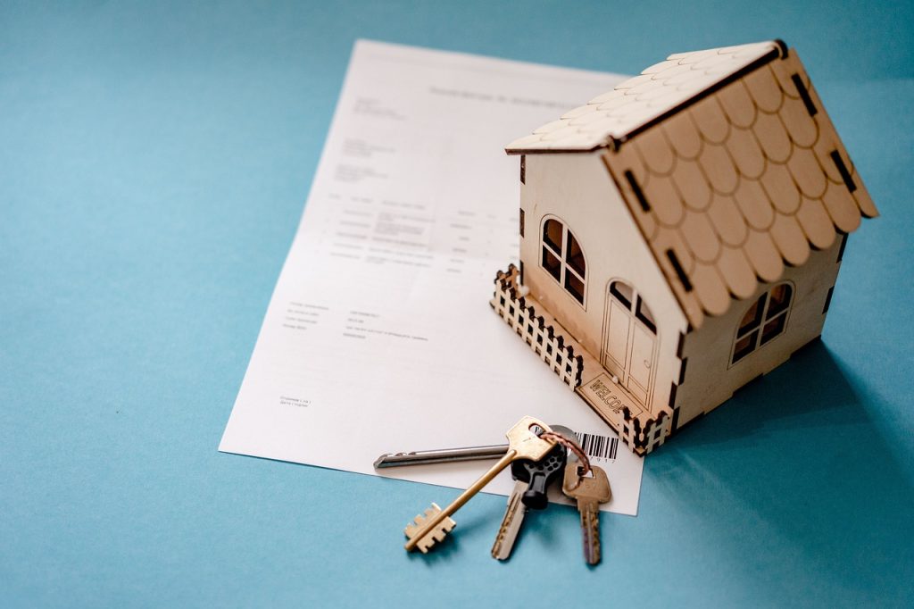 Conceptual arrangement of real estate documents, home loan papers, and property ownership items on a surface.
