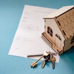 Conceptual arrangement of real estate documents, home loan papers, and property ownership items on a surface.