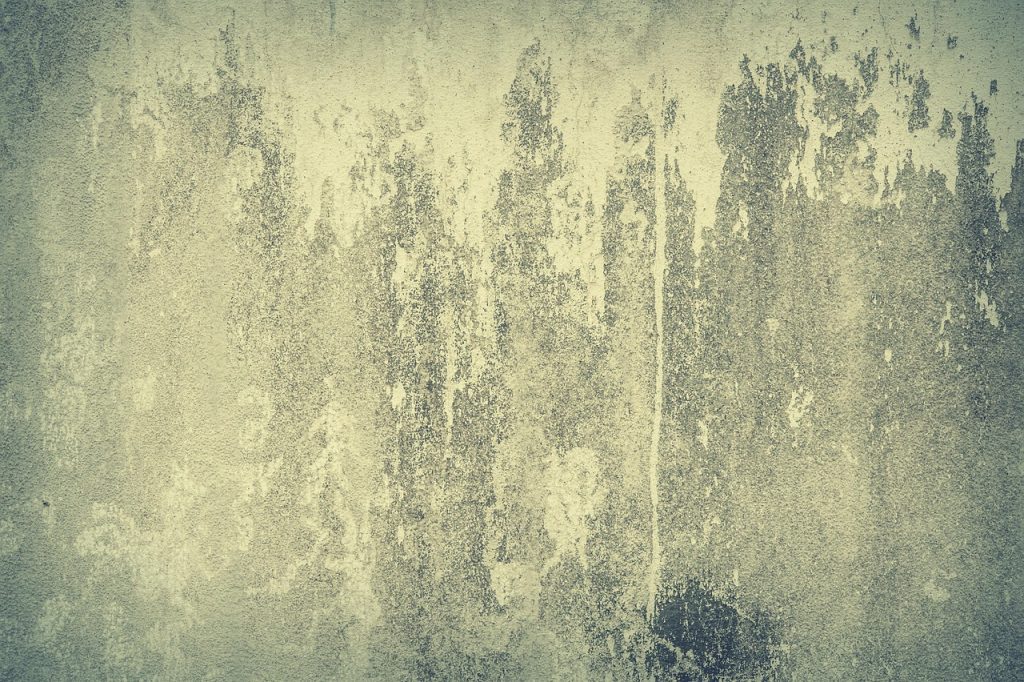 Close-up of an aged, weathered concrete wall with a rough, grunge-textured surface and abstract patterns.