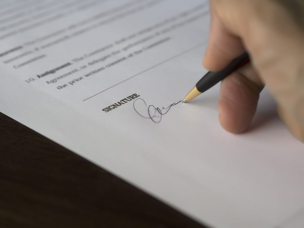 A hand poised with a pen over a contract document, ready to sign.