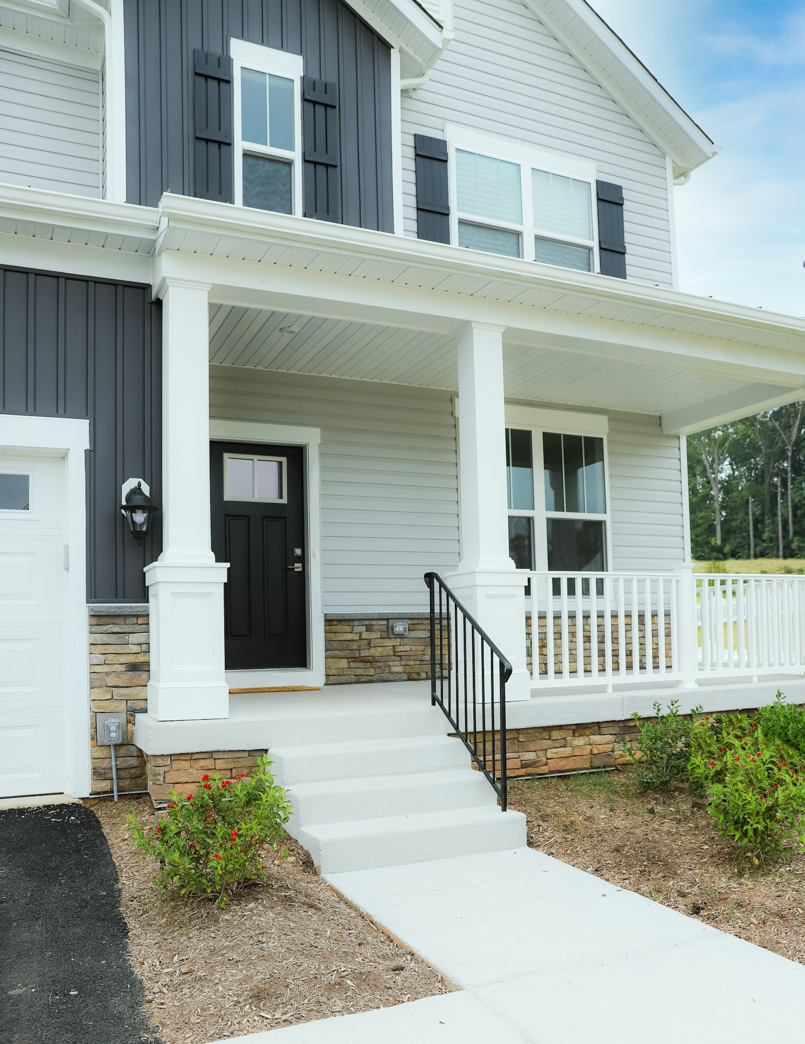 Finished new construction home with a white exterior and black front door
