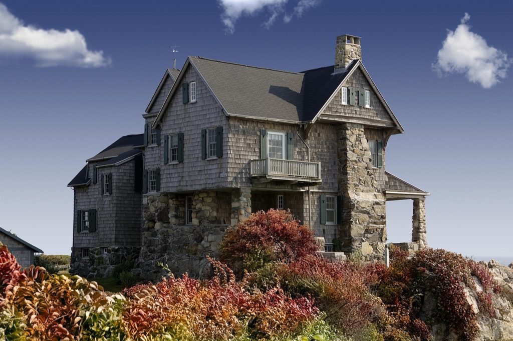 Large stone house with masonry facade set within a landscape.