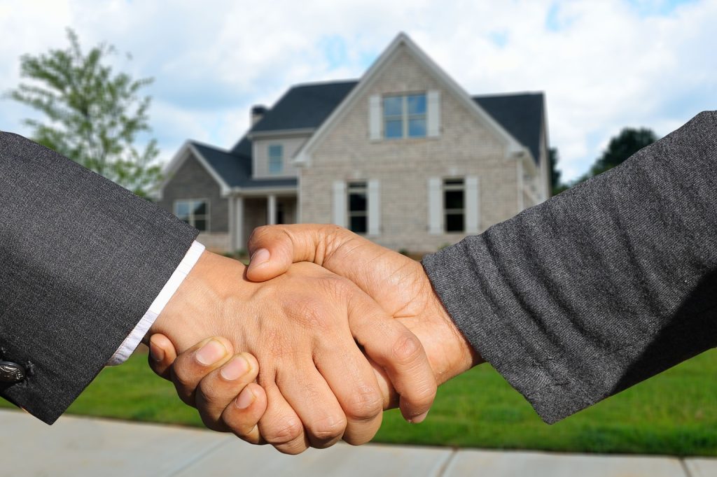 A real estate agent handing over property documents during a house purchase transaction.