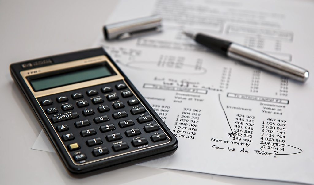 A calculator and fountain pen resting on financial documents, representing insurance accounting and tax calculation work.