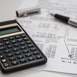 A calculator and fountain pen resting on financial documents, representing insurance accounting and tax calculation work.